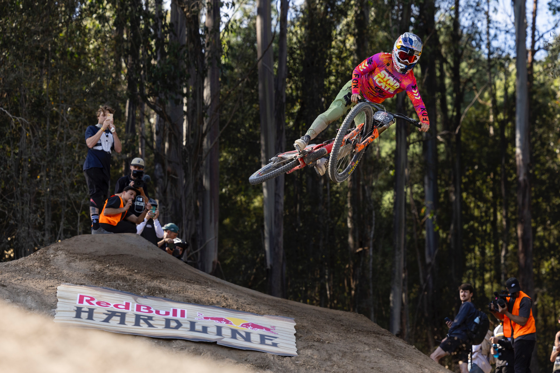 Rider whipping the bike mid-air over a dirt jump at Maydena